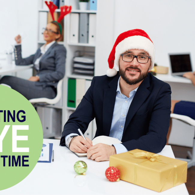 A man sits in an office wearing a santa hat